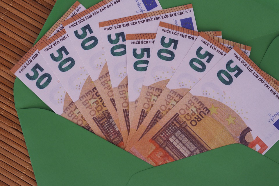 banconote da 50 euro disposte a ventaglio spuntano fuori da una busta da lettera verde