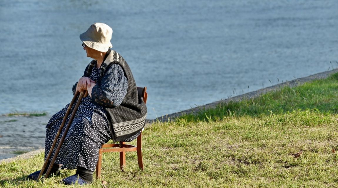 Anziana signora che siede in riva al lago