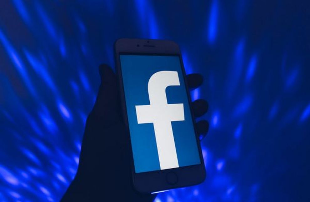 logo di facebook su smartphone su sfondo a luci blu