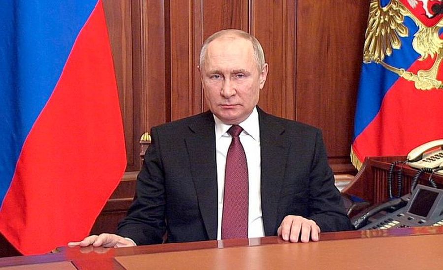 Putin alla scrivania con bandiere alle spalle