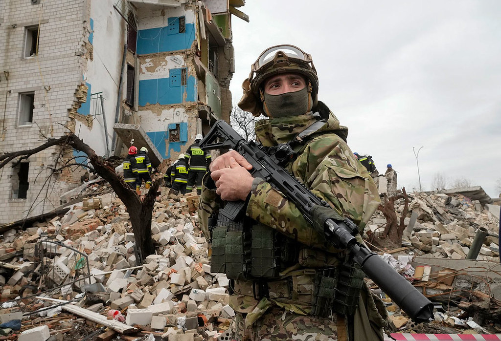 soldato ucraino di fronte ad edificio distrutto dalle bombe