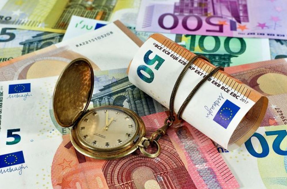 orologio a cipolla poggiato su banconote di euro di vario taglio
