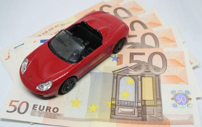modellino di automobile poggiato su banconote da 50 euro disposte a ventaglio