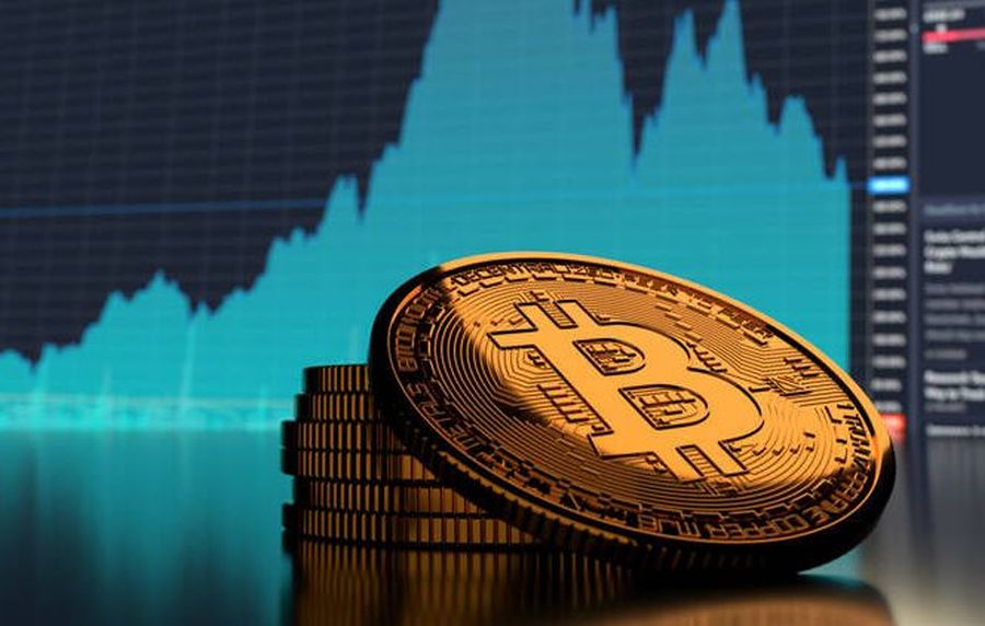 gettone di Bitcoin e sullo sfondo un grafico sull'andamento di prezzo