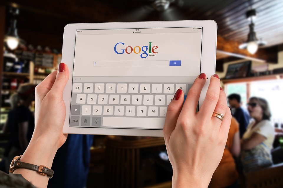 le mani di una donna su un tablet che visualizza la pagina di ricerca di google