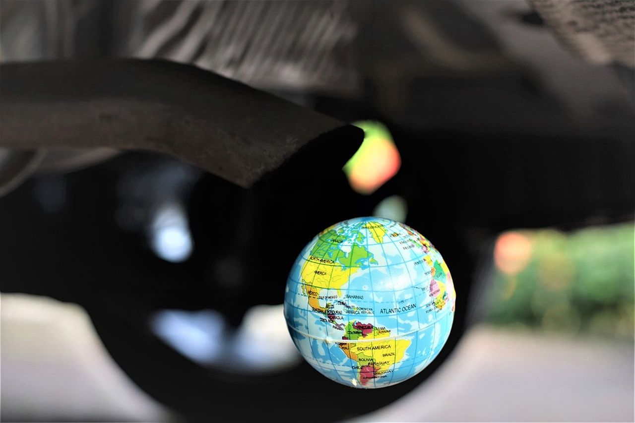 fotomontaggio con lo scarico di un'automobile rivolto verso il globo di un mappamondo