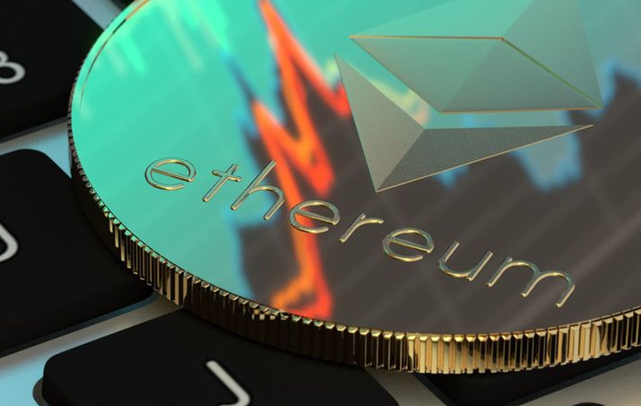 una moneta di Ethereum su una tastiera, con un grafico riflesso sulla superficie lucida