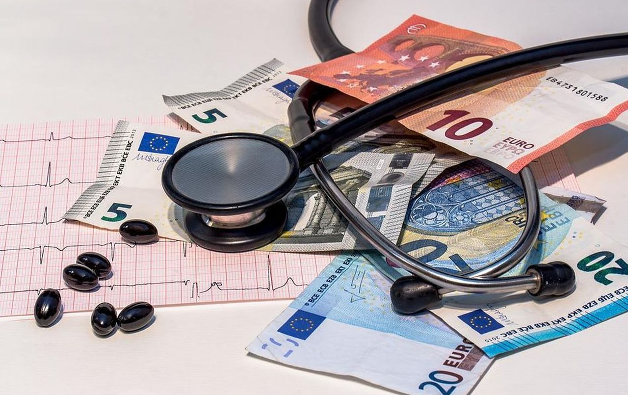 uno stetoscopio e alcune pasticche tra banconote di euro e ricette mediche