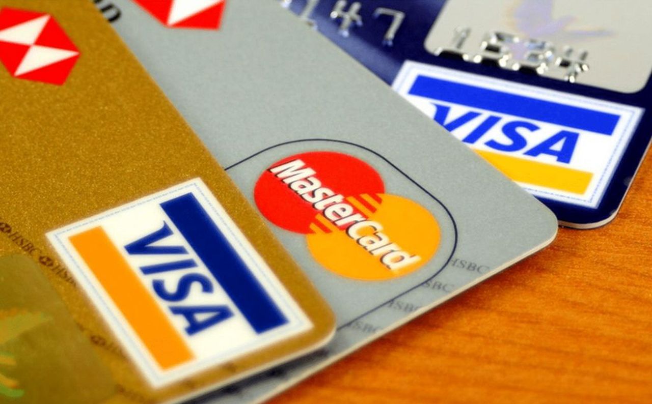 alcune carte di pagamento, Visa e Mastercard, disposte a ventaglio su una superficie di legno