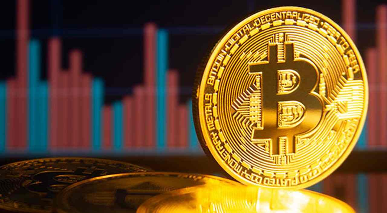 una moneta di Bitcoin con un grafico sull'andamento dei prezzo sullo sfondo