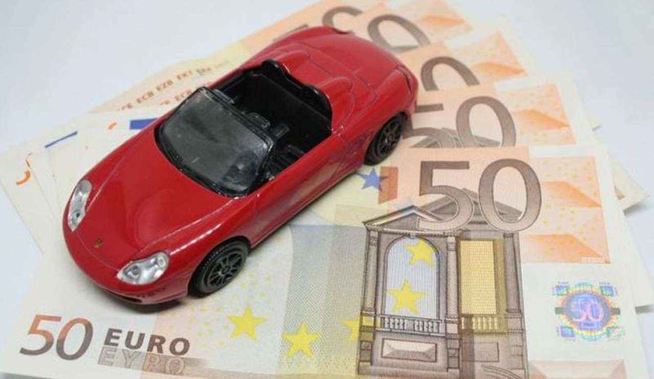 modellino di automobile poggiato su banconote da 50 euro disposte a ventaglio