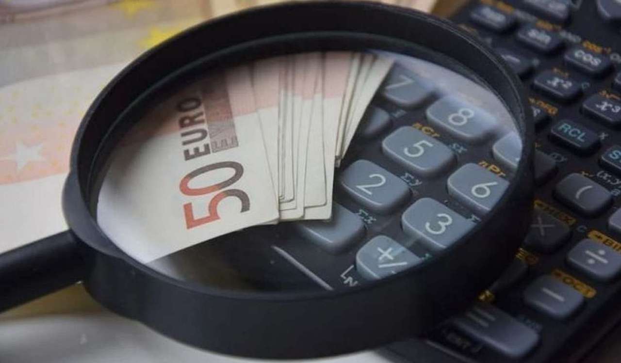 una lente d'ingrandimento su una calcolatrice e alcune banconote da 50 euro