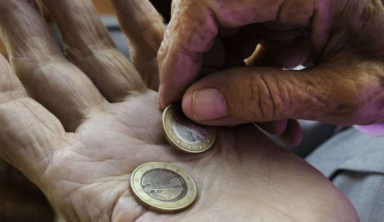 due monete da 1 euro nel palmo della mano di un anziano