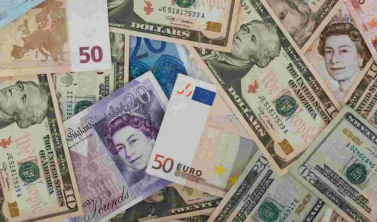 alcune banconote di euro e di dollaro disposte in modo arruffato su un piano