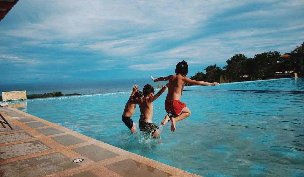 la piscina di un resort con alcuni ragazzini che saltano in acqua