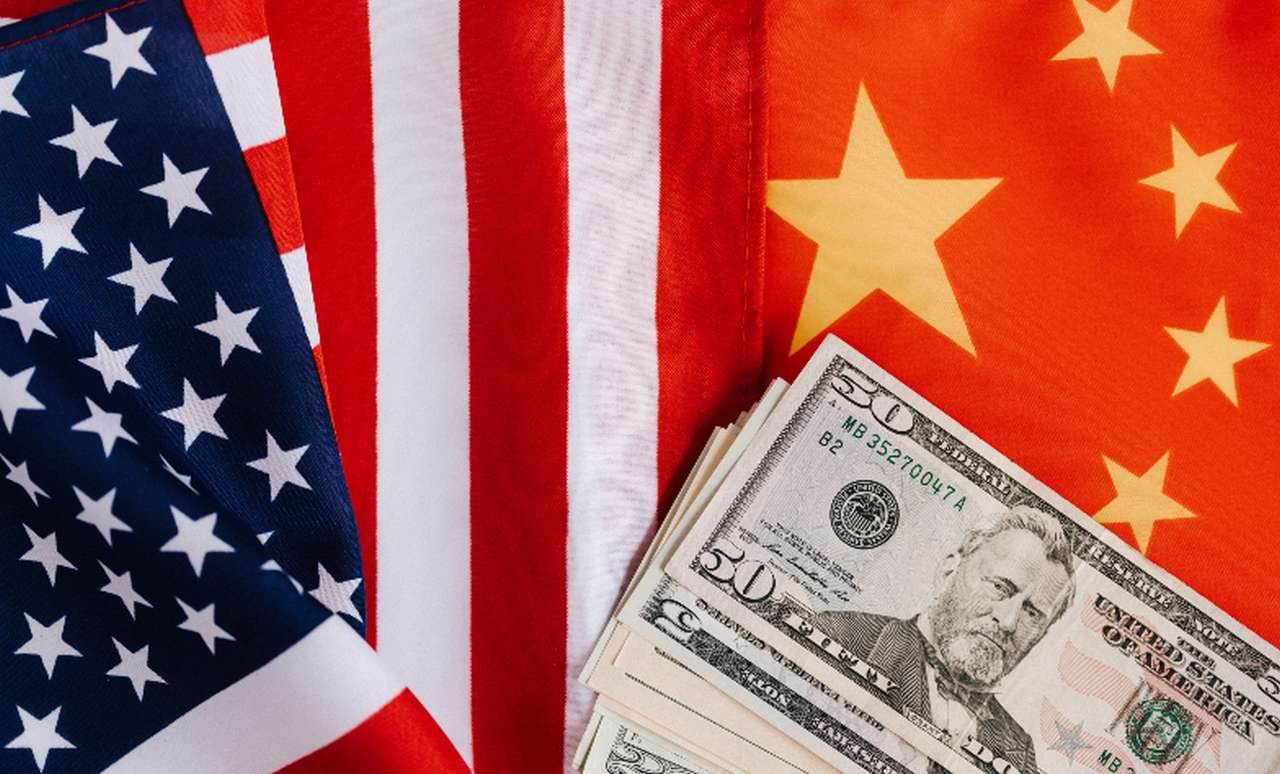 la bandiera degli Usa a sinistra e quella della Cina a destra, con una mazzetta di dollari su di essa