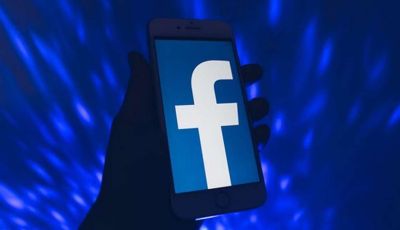 logo di facebook su smartphone su sfondo a luci blu