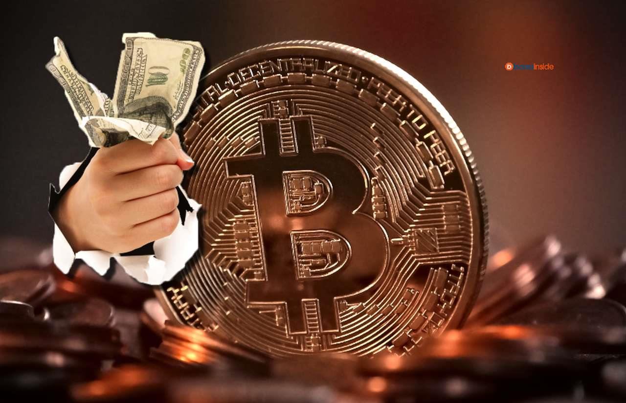 una moneta di Bitcoin e delle banconote di dollari strette in un pugno