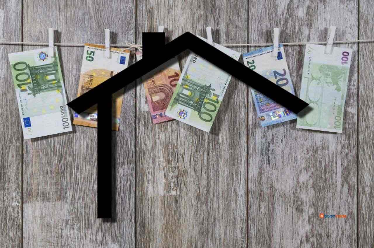 La sagoma di una casetta stilizzata con delle banconote di euro appese su un filo sullo sfondo