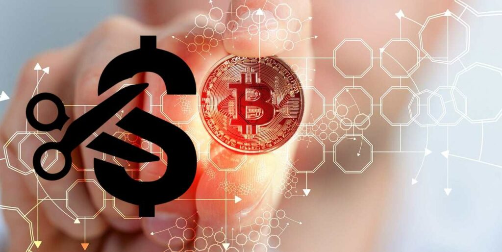 moneta Bitcoin tra le mani e forbice che taglia dollari