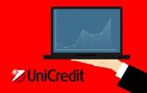 logo di Unicredit e monitor con grafico di trading