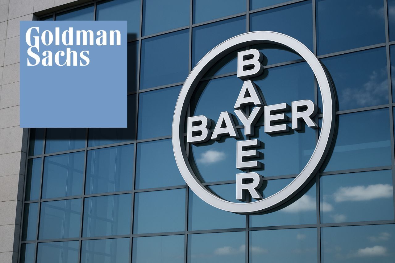Il logo Bayer sulla vetrata di un palazzo. In sovrimpressione in alto a sinistra il logo di Goldman Sachs