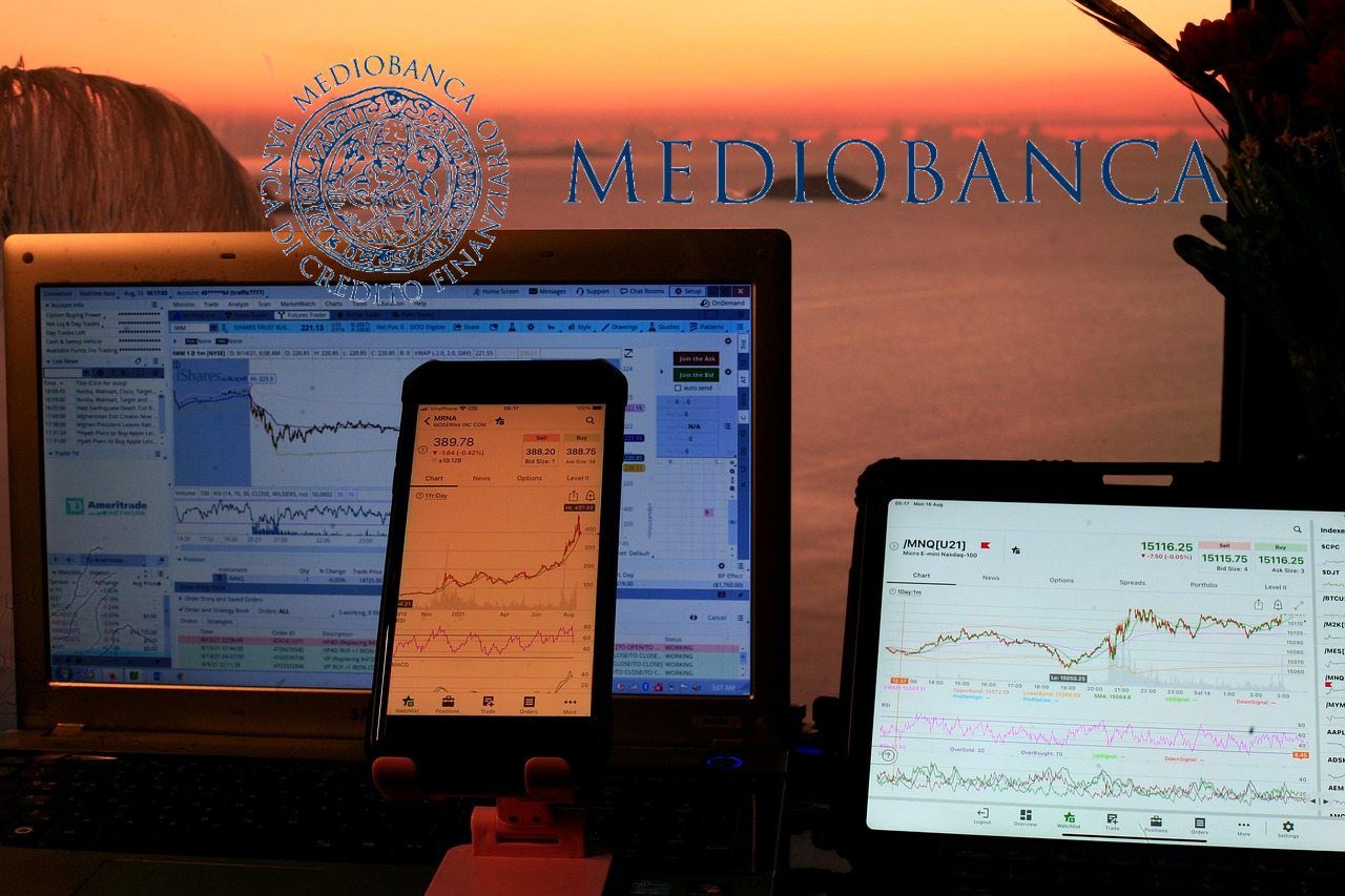 logo di Mediobanca e tablet con grafici di trading