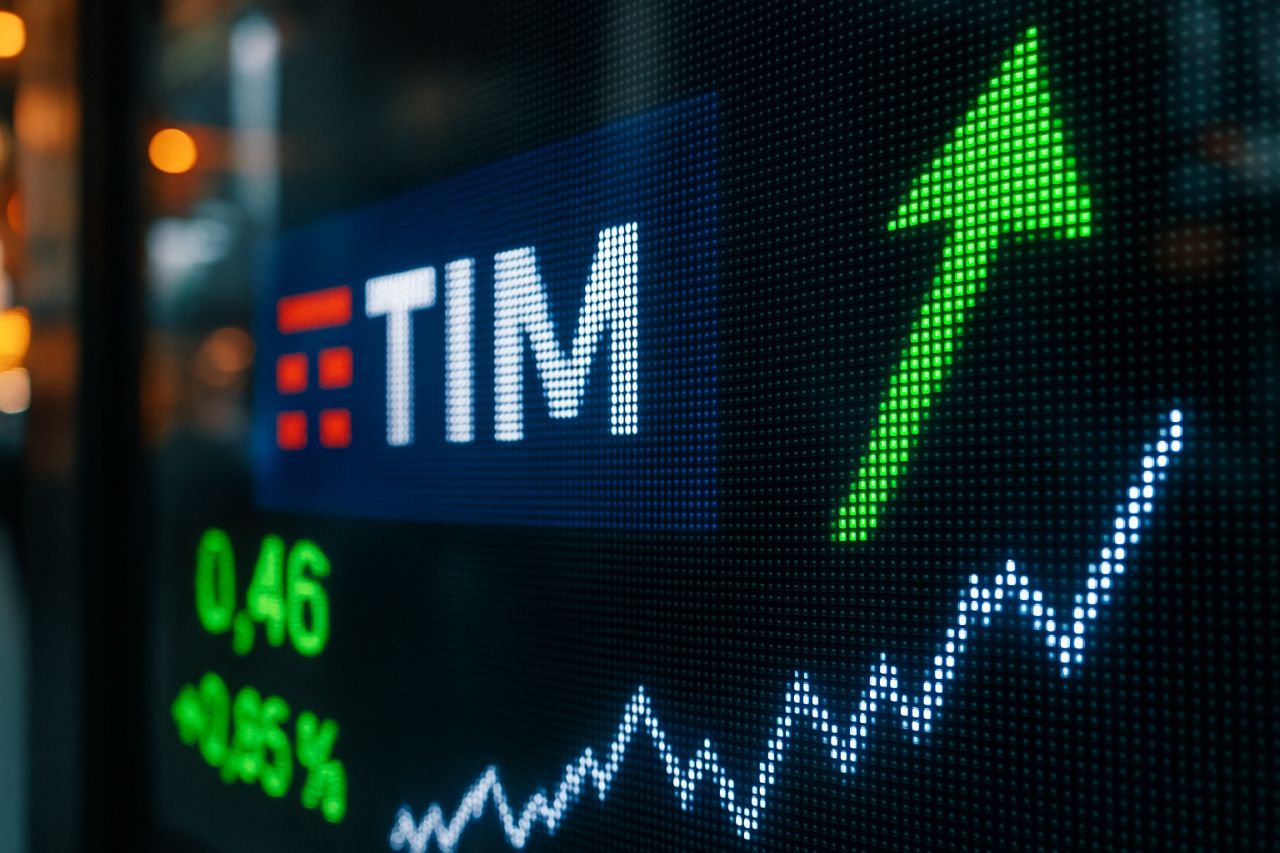 uno schermo con l'andamento di alcuni titoli, il logo di TIM e una freccia verde verso l'alto