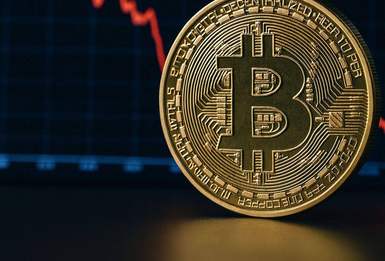 Una moneta di Bitcoin con un grafico in discesa sullo sfondo