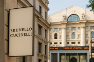 l'edificio della Borsa di Milano con un'insegna a bandiera in primo piano con la scritta Brunello Cucinelli