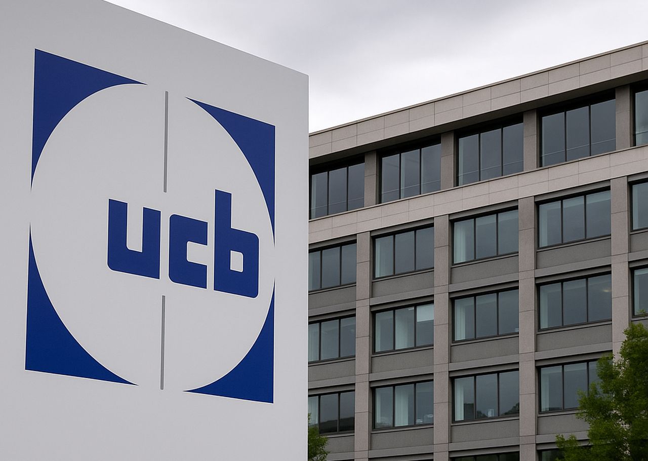 Un totem pubblicitario con la scritta ucb e un palazzo sullo sfondo