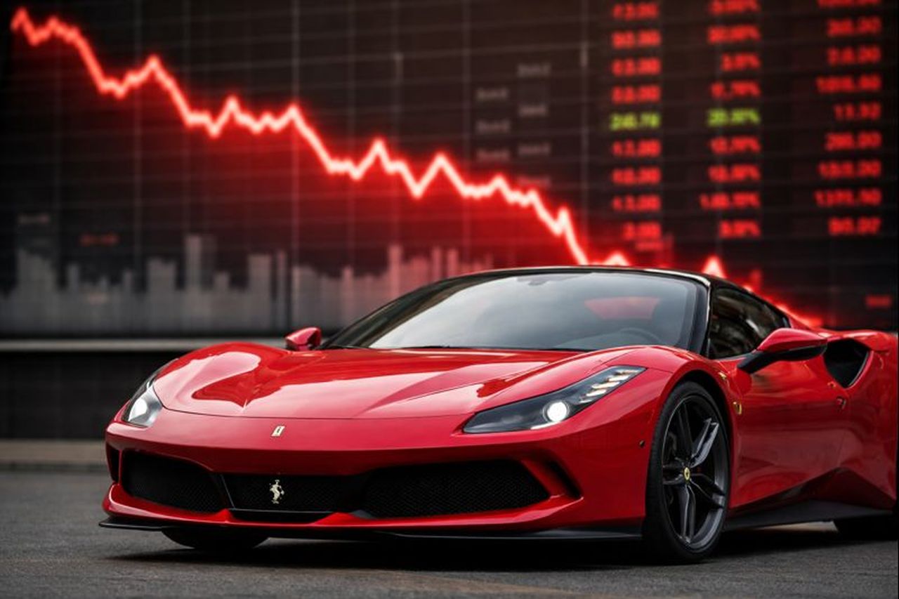 Una Ferrari con uno schermo gigante alle spalle che mostra un grafico finanziario in discesa
