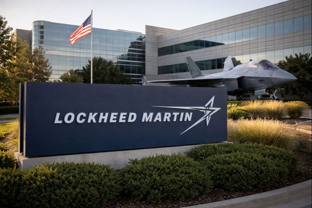 Insegna con logo Lockheed Martin davanti a un edificio con un caccia F 35 parcheggiato davanti