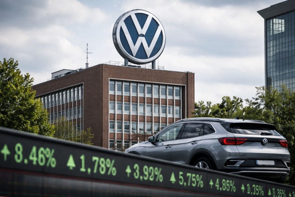Auto Volkswagen parcheggiata davanti a un edificio aziendale con il grande logo VW sul tetto